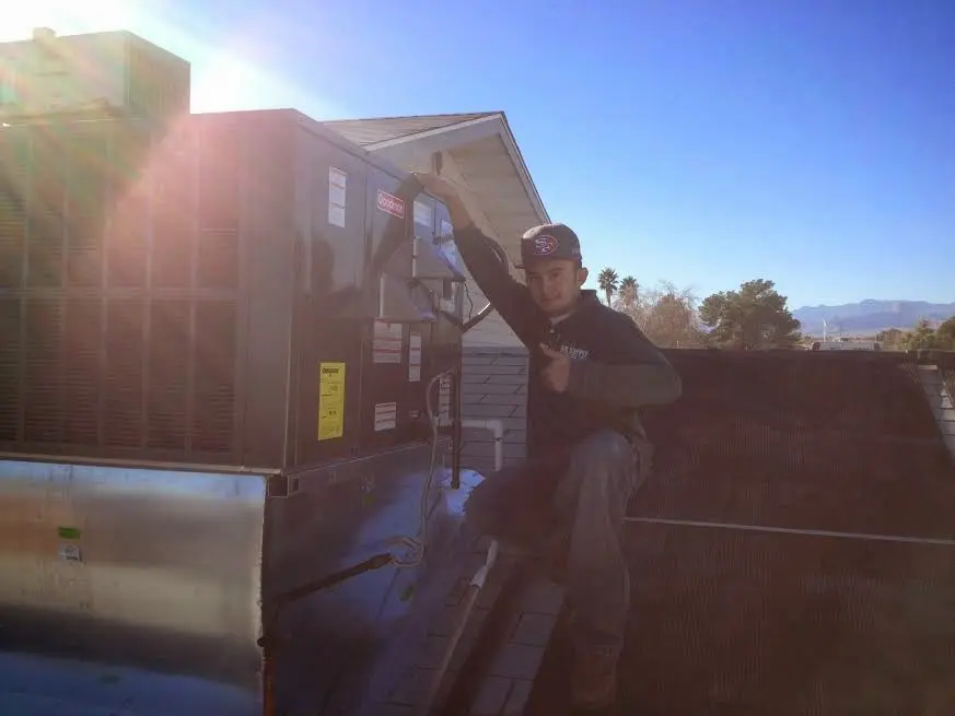 HVAC technician performing Air Duct Cleaning on a rooftop unit in Buckley